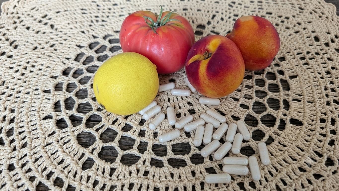 Cásulas de colágeno, limón, tomate y nectarinas sobre paño de ganchillo beige